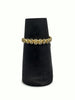 Gold bracelet on a black velvet stand against a white background